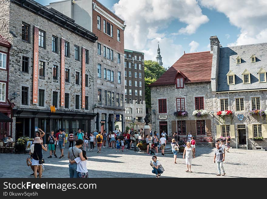 People Near Gray Concrete Buildings Under Blue Sky and White Clouds