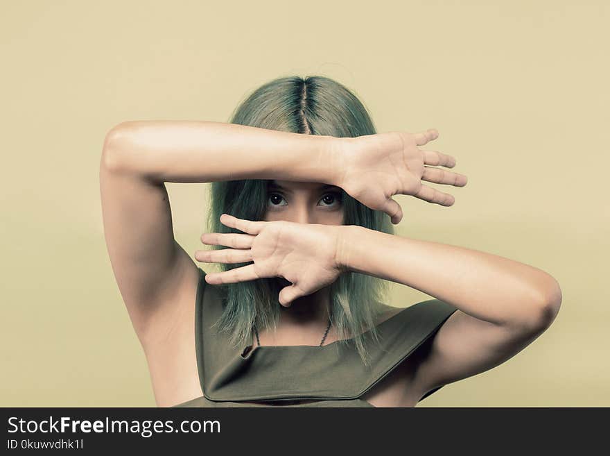 Woman Wearing Green Sleeveless Top Covering Her Face but Eyes With Both Hands