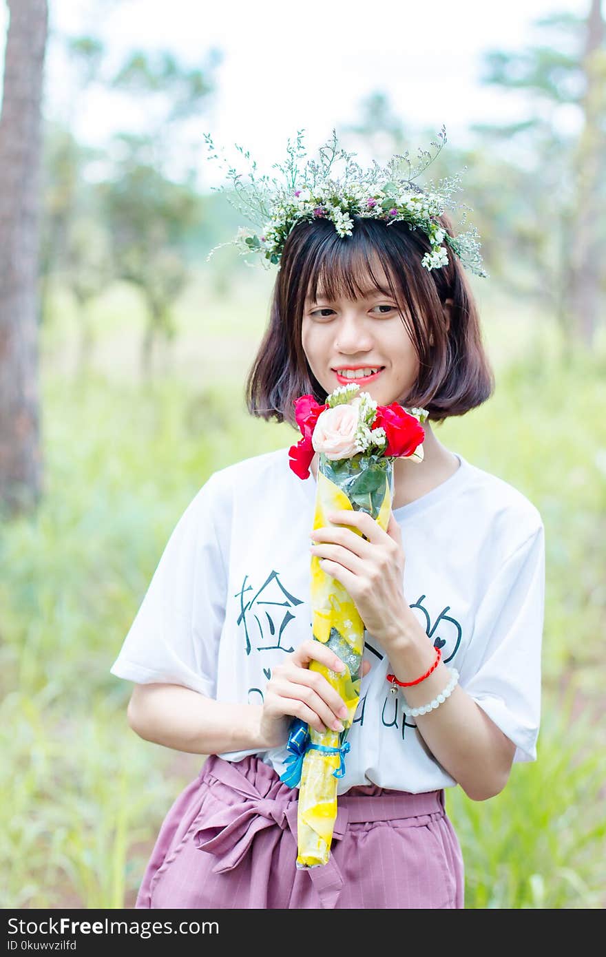 Woman Wearing White Shirt and Purple Bottoms Holding Bouquet of Flowers