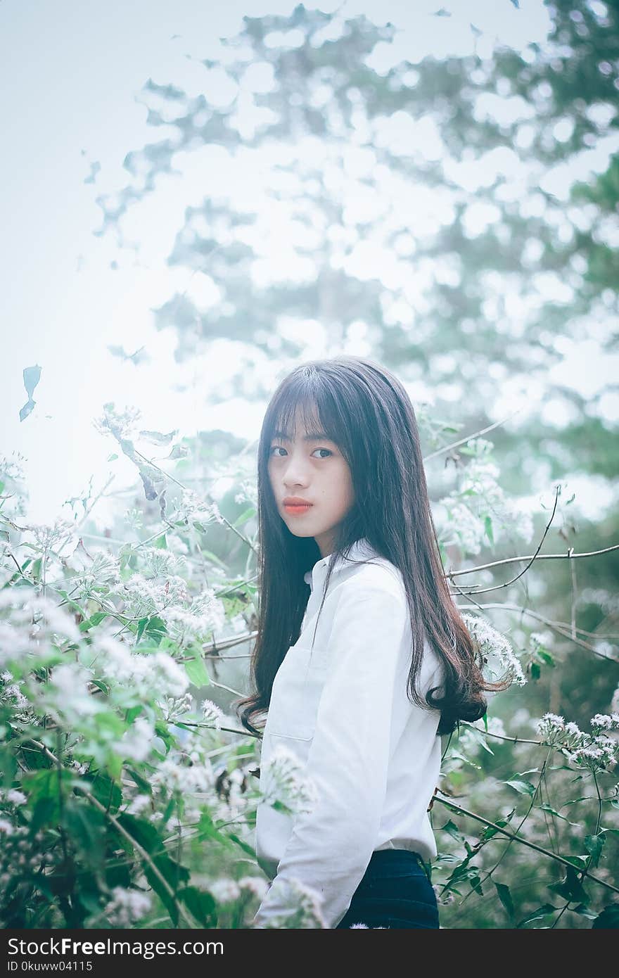 Woman Wearing White Button-up Long-sleeved Collared Shirt Standing Beside White Petaled Flower