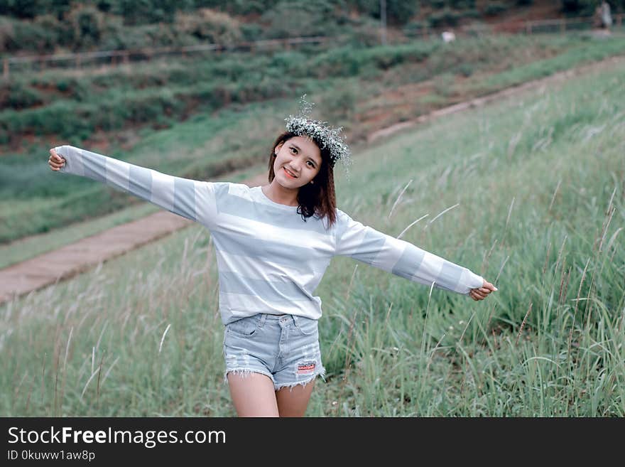 Selective Focus Photo of Woman Wearing Gray and White Striped Sweatshirt Standing on Green Grass Fields