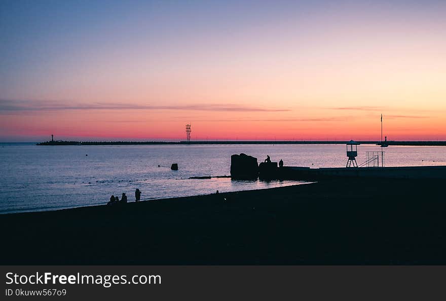 Silhouette of Seashore With Group of People in Front Body of Water