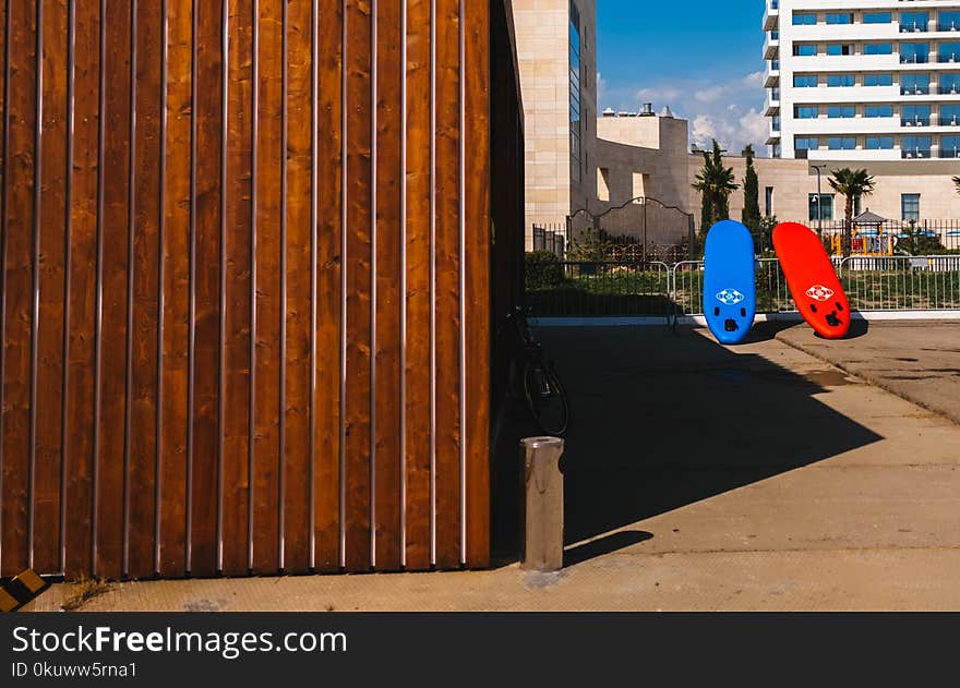 Red and Blue Surfboards Near Brown Wooden House