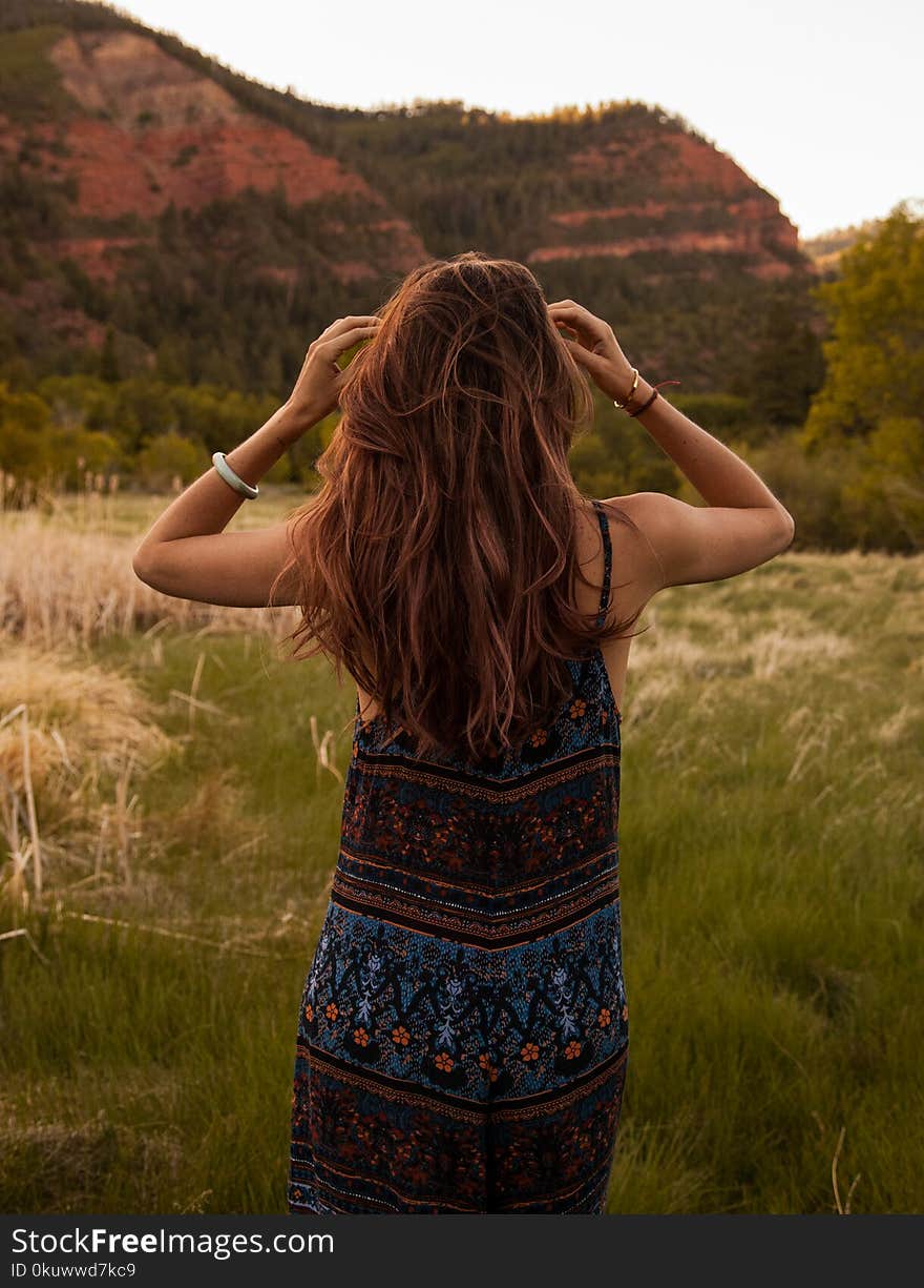 Woman Wearing Red and Blue Floral Dress Standing Beside Mountain