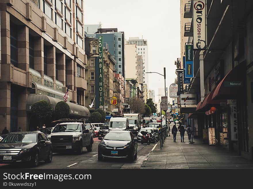 Busy Street With Vehicles and People Walking Beside Buildings