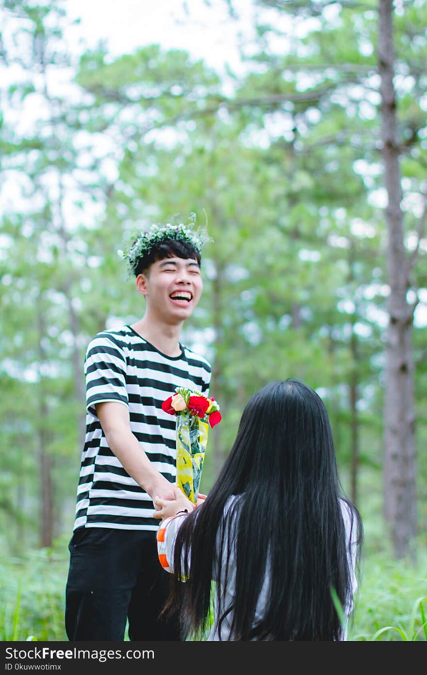 Man Wearing White and Black Striped Crew-neck Shirt Holding Red and Yellow Flowers