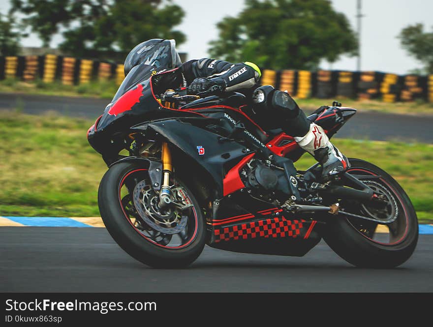 Man With Black Alpinestar Racing Suit Riding Black and Red Sports Bike