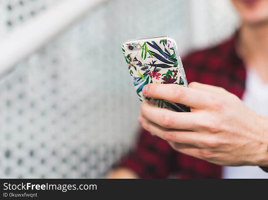 Person Holding Smartphone With White and Green Floral Case