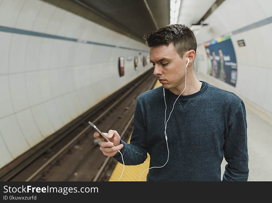 Man looking at a phone with earphones on