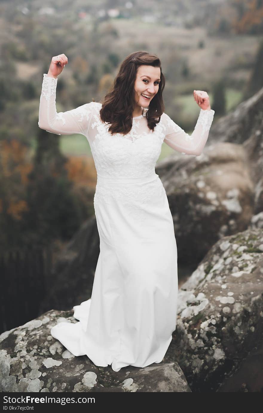 Beautiful happy bride outdoors in a forest with rocks. Wedding perfect day.