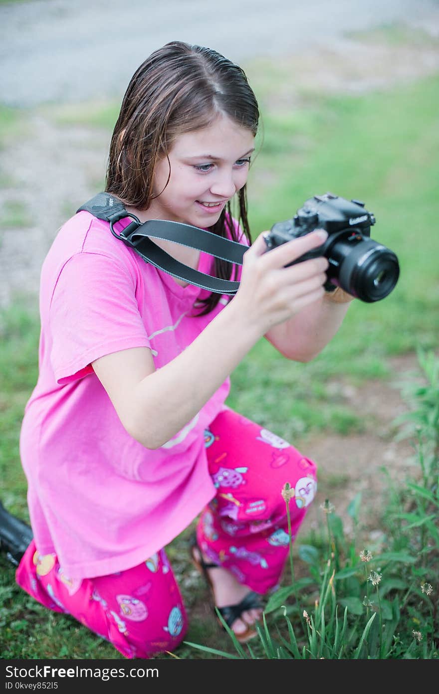 Shallow Focus Photo of a Girl in Pink Round-neck Shirt Holding Black Dslr Camera