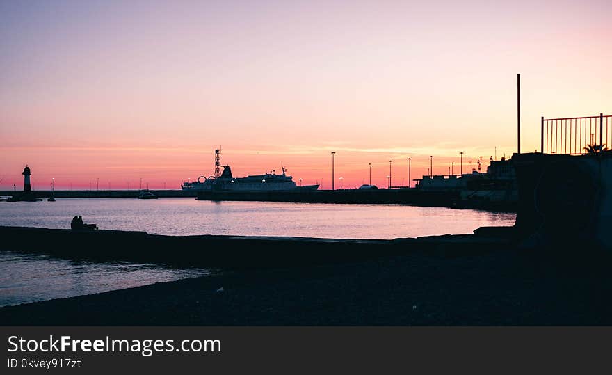 Silhouette of Boat Dock Near Water during Dawn