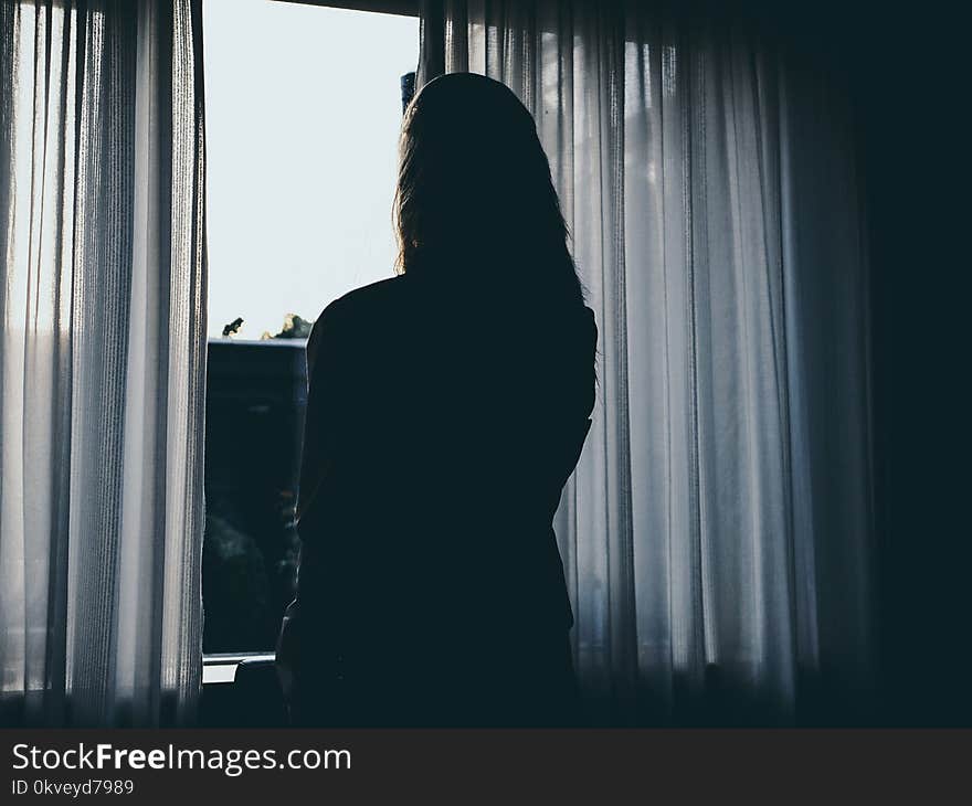 Silhouette Of Woman Standing Beside Window