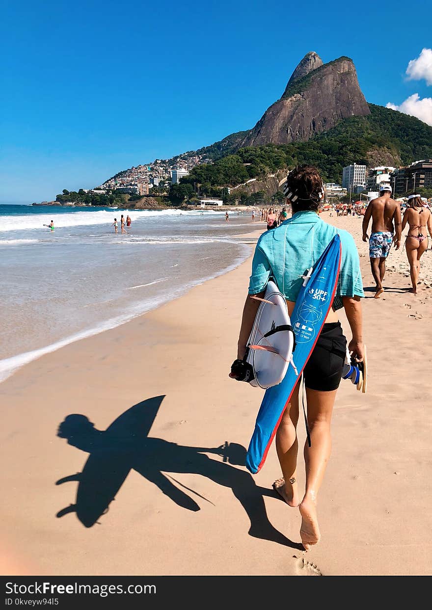 Person In Teal Top And Black Shorts Walking On Seashore