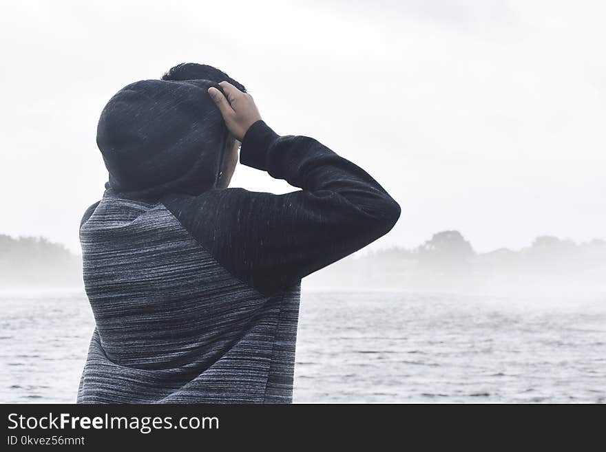 Person in Black and Grey Raglan Hoodie Near Body of Water