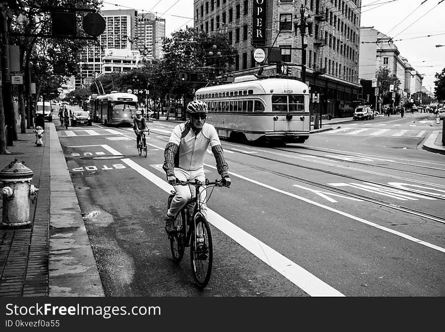 Grayscale Photo of Man Riding Bicycle on Street