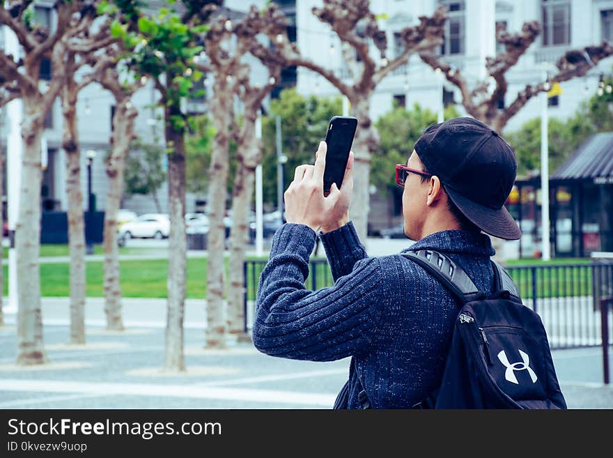 Man Wearing Black Jacket and Holding Black Android Smartphone