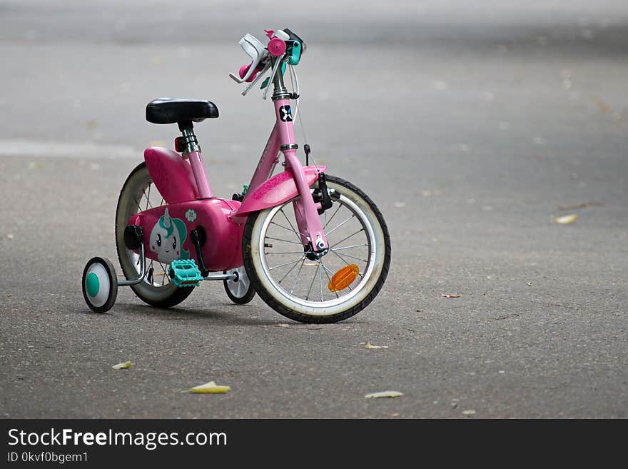 Pink Bike With Training Wheels on Gray Pave Road