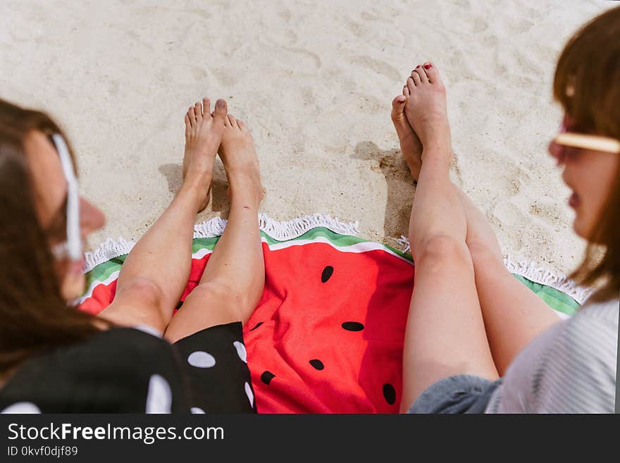 Two Person Sitting on Sand While Taking at Daytime