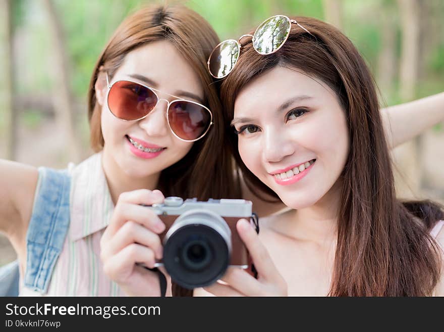 Two beauty women take camera and go travel happily in the forest. Two beauty women take camera and go travel happily in the forest