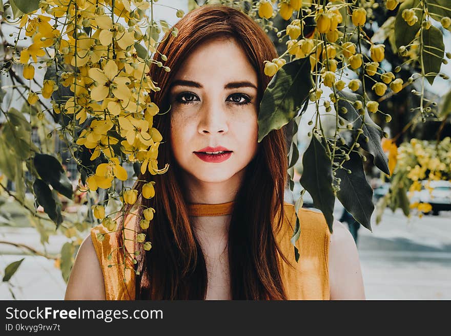 Woman Wearing Yellow Sleeveless Top Standing Near Flowers