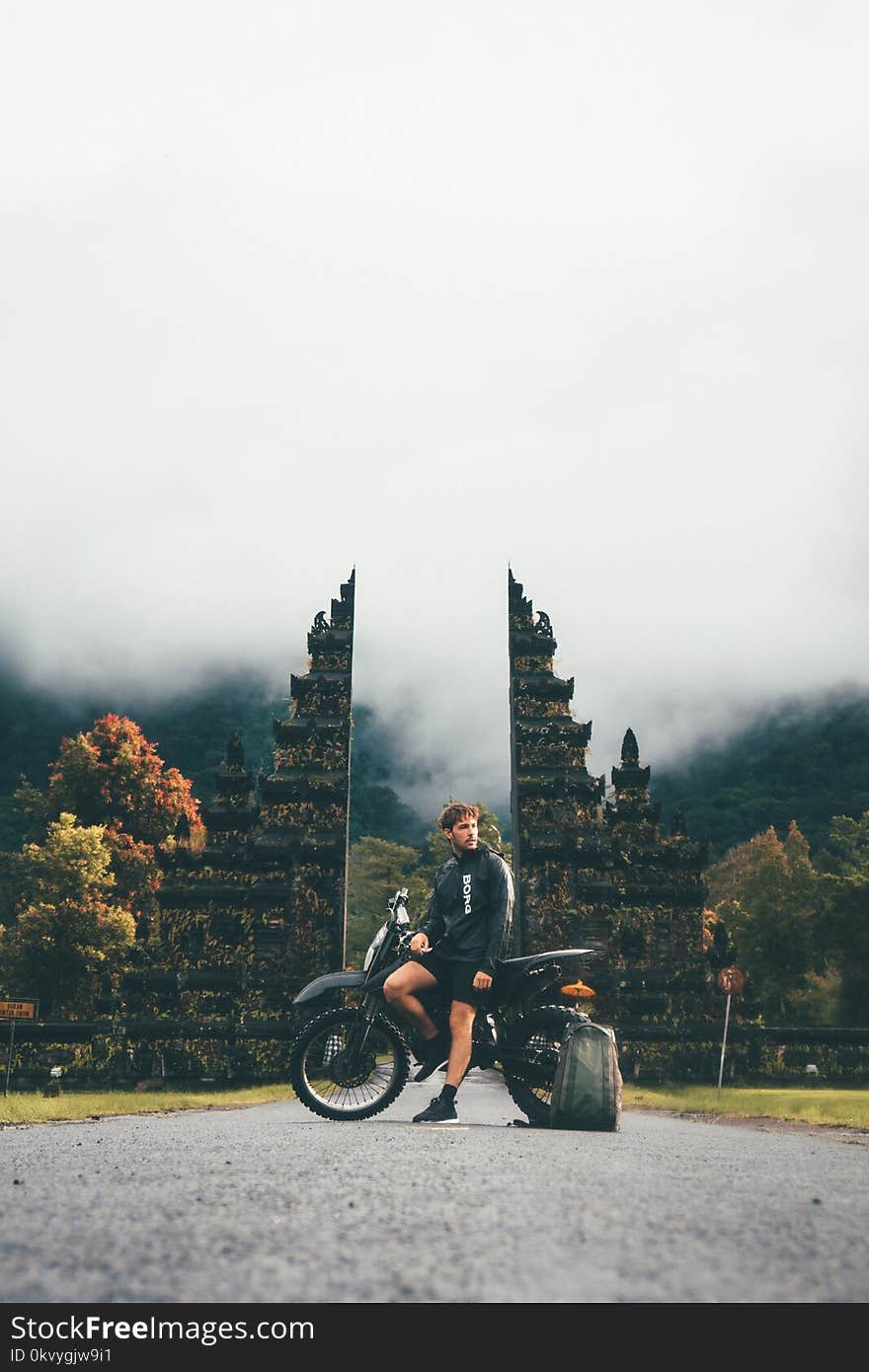 Photo of Man Sitting on Motorcycle Near Tower