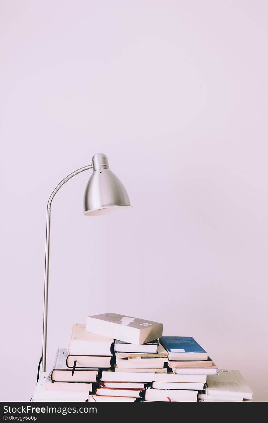 Silver Desk Lamp Near Pile of Books