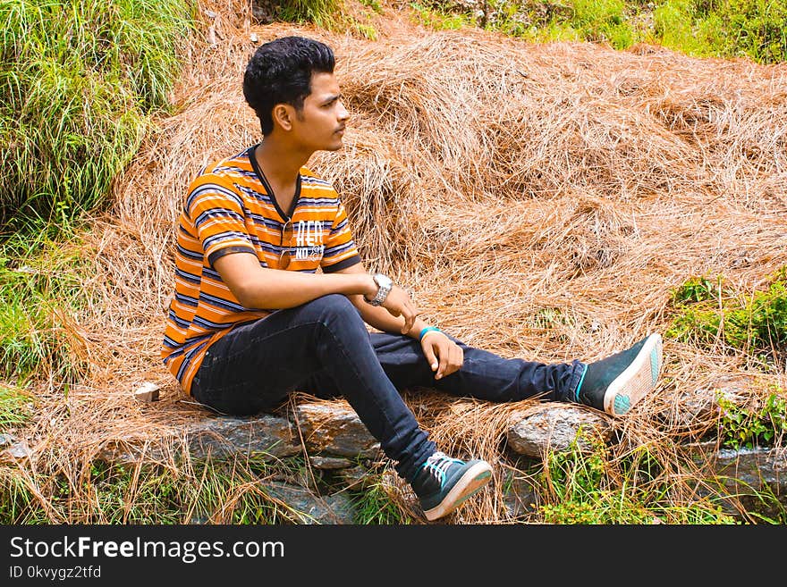 Man Wearing Blue Jeans Sitting on Brown Hay