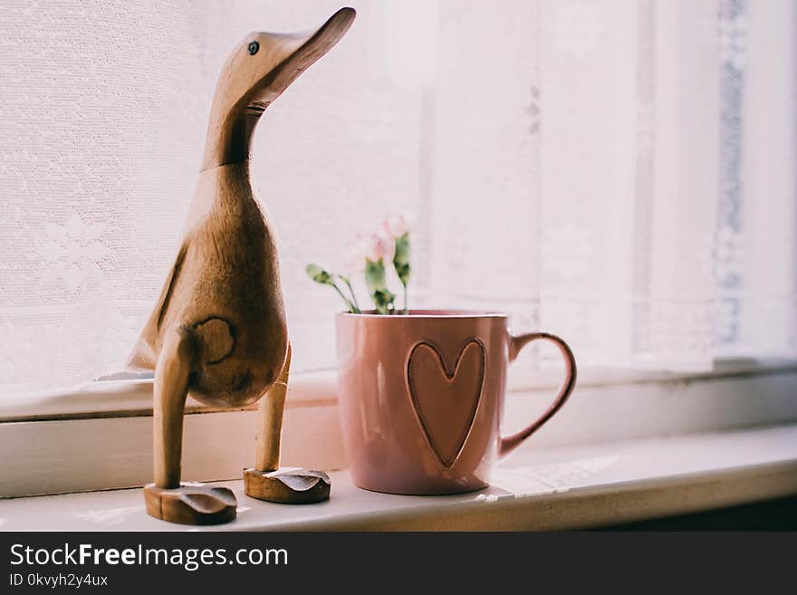 Brown Wooden Duck Figurine Near Brown Ceramic Mug