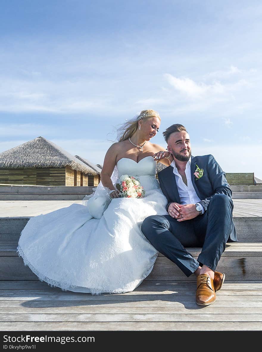 Woman Wearing White Wedding Gown Sitting Near Man Wearing Black Suit Jacket and Pants