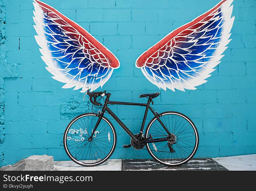 Black Road Bike Leaning on Red-blue-and-white Wing Graffiti Wall