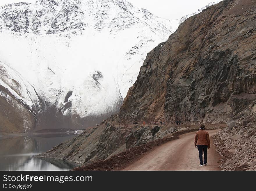 Woman With Brown Jacket Walking Beside Body of Water