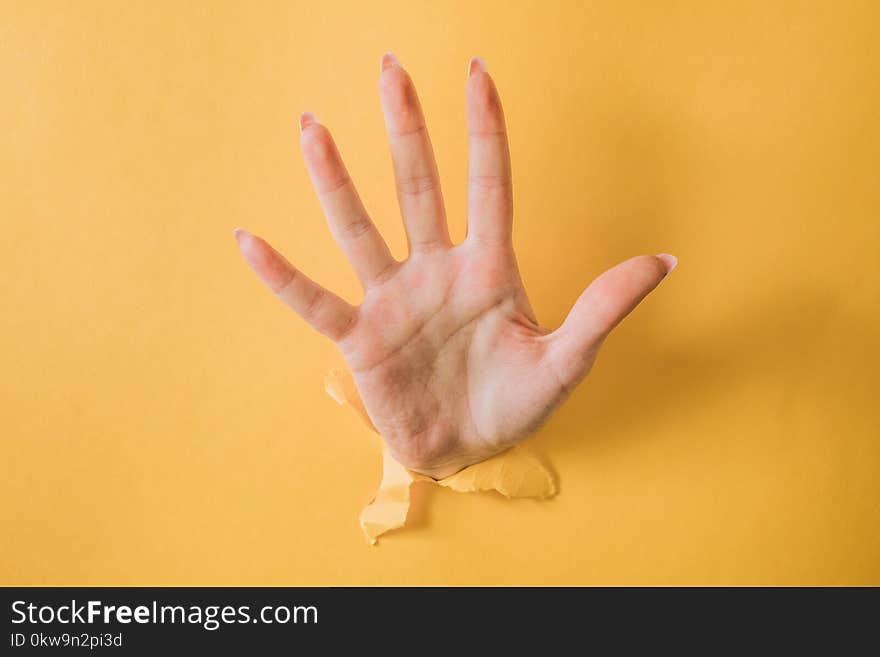 girl hand breaks the yellow paper and shows a gesture