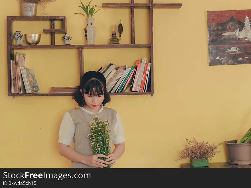 Woman Holding White Bouquet of Flowers Near Wall