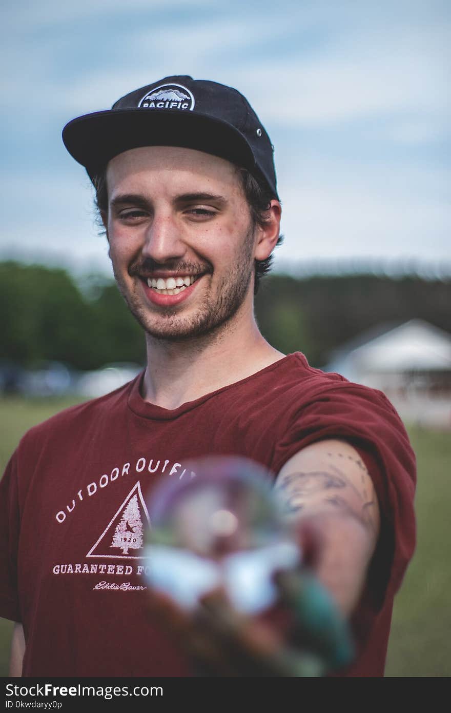 Smiling Man Wearing Maroon Shirt and Black Cap