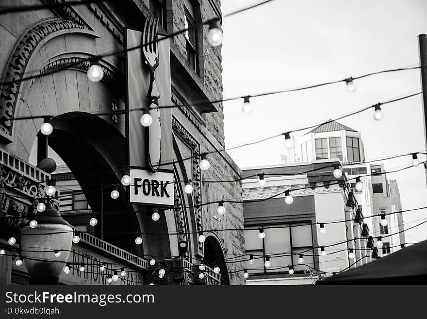 Grayscale Photography of Light Bulbs Near Concrete Buildings