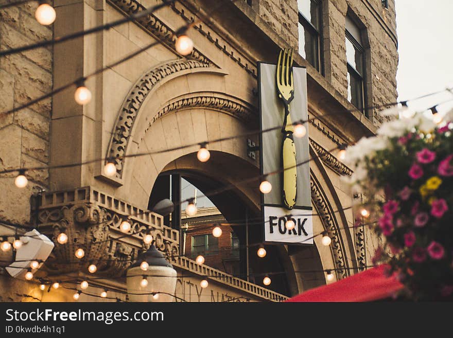 Grey and Black Fork Signage Hanging on Brown Concrete Building