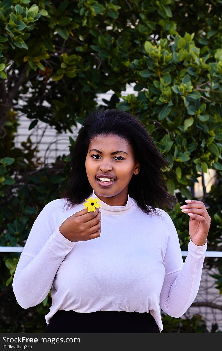 Woman in Purple Turtleneck Sweatshirt Holding Yellow Petaled Flower