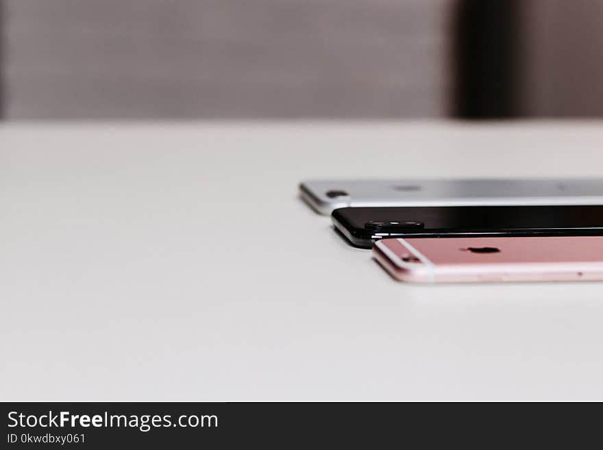 Three Assorted-color Iphone on White Wooden Desk