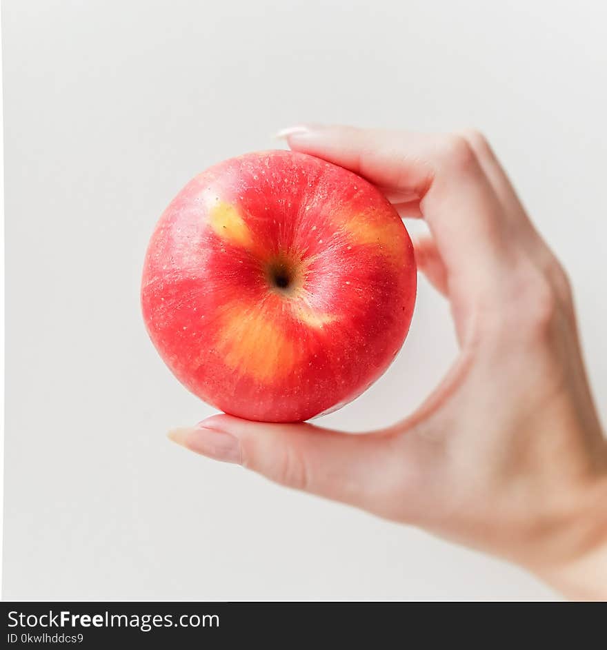 Ripe red apple in hand. White bakcground. Side view