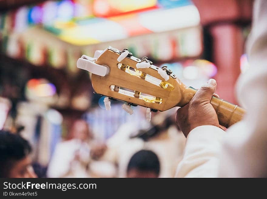 Close up of a guitar head and tuning pegs as a man is playing it in a restaurant