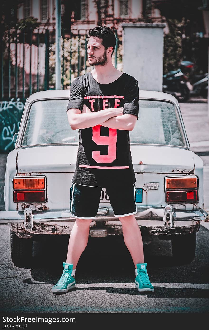 Man Wearing Black Scoop-neck T-shirt and Black Gym Shorts Standing Behind White Vehicle