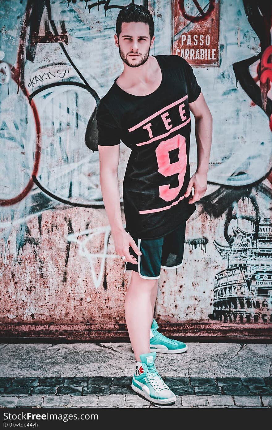 Man Wearing Black and Pink Tee 9-printed T-shirt in Front of Wall