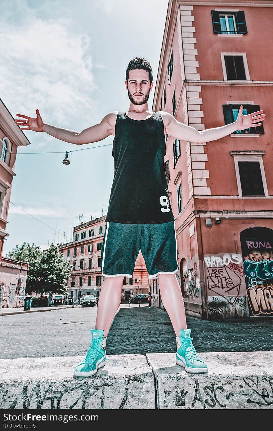 Man In Black Tank Top And Green Shorts Posing Near Building