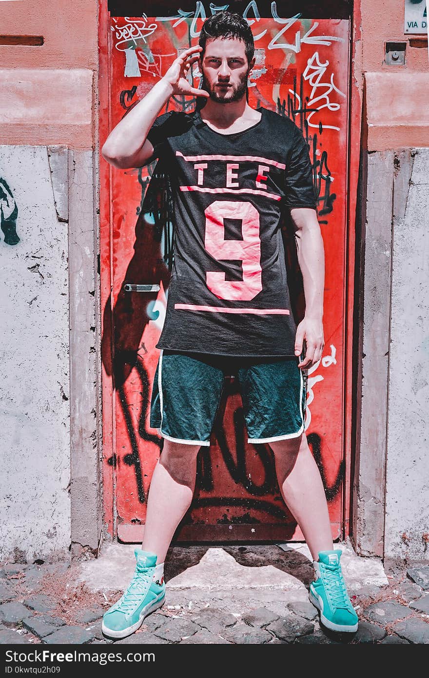 Man Wearing Black T-shirt Standing Near Red Metal Door