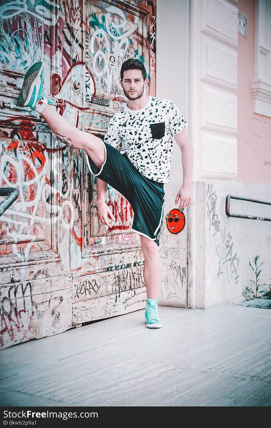 Man Wearing Black and White Crew-neck T-shirt With Right Foot Up