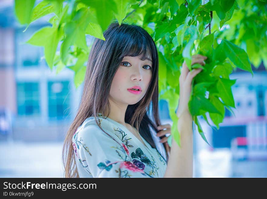 Woman Wearing White and Pink Floral Shirt Holding Leaf