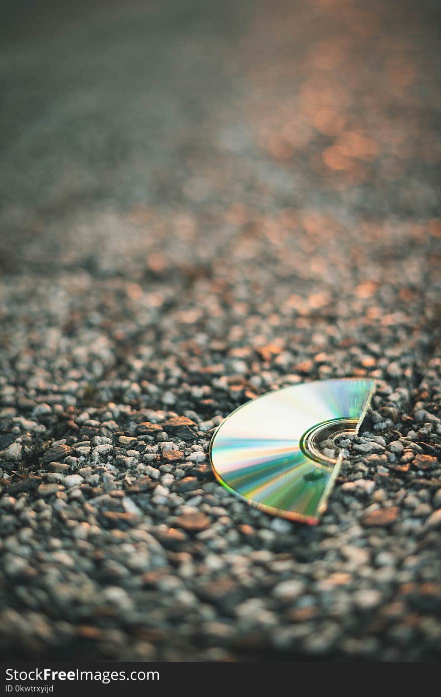 Selective Focus Photography of Half Cut Compact Disc on Gray Pavement