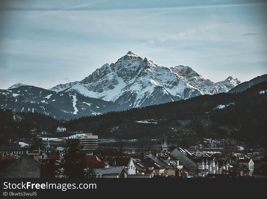 Snow Covered Mountain Near Village Under Blue Sky