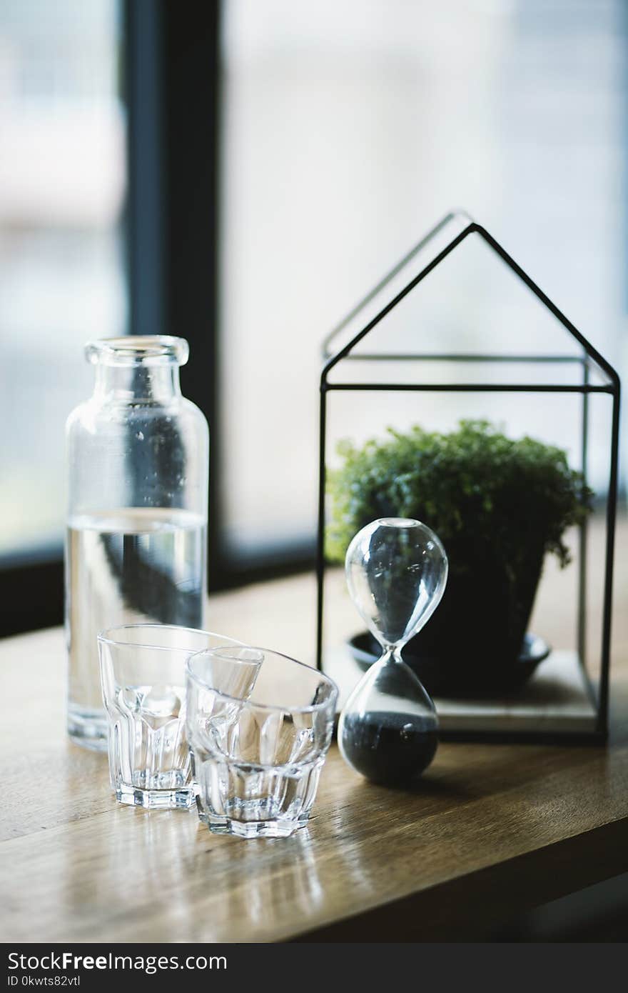 Shot Glasses and Hourglass on Brown Wooden Surface